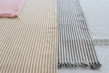 Load image into Gallery viewer, The placemat features olive green and taupe stripes accented with fringing to create a casual, yet done tablescape. We love the brand because all Raine and Humble textiles are made in their own factory in India by third generation cotton producers. Everything is ethically produced using traditional dying methods and innovative weaving and washing methods to give different textures. All employees are paid fair wages and work in ideal working conditions with no child employment.